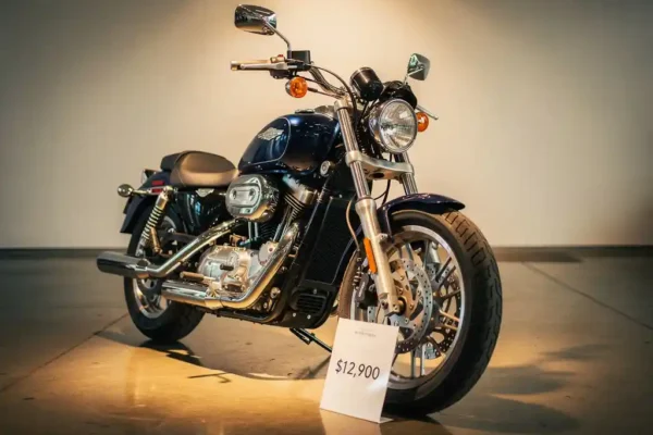 Gloednieuwe marineblauwe motorfiets met glanzend chroom in showroom, prijskaartje tegen de band, verlicht door warm spotlight.